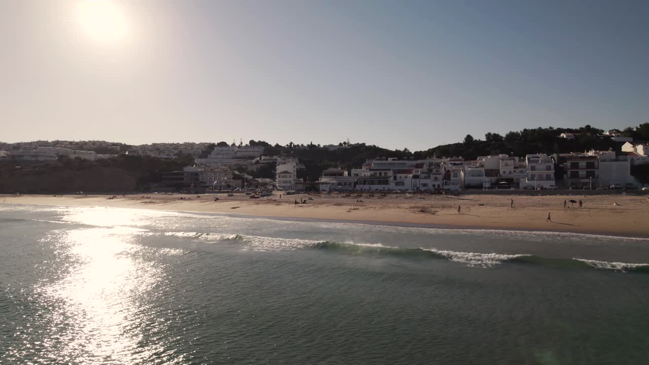 gente disfrutando de los últimos rayos de sol del día en la playa de salema, portugal