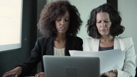 dos empresarias de contenido sentadas juntas y leyendo informes