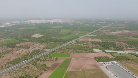 Wide-aerial-footage-of-a-highway-outside-of-the-city-of-Bari,-Italy-in-the-afternoon-haze