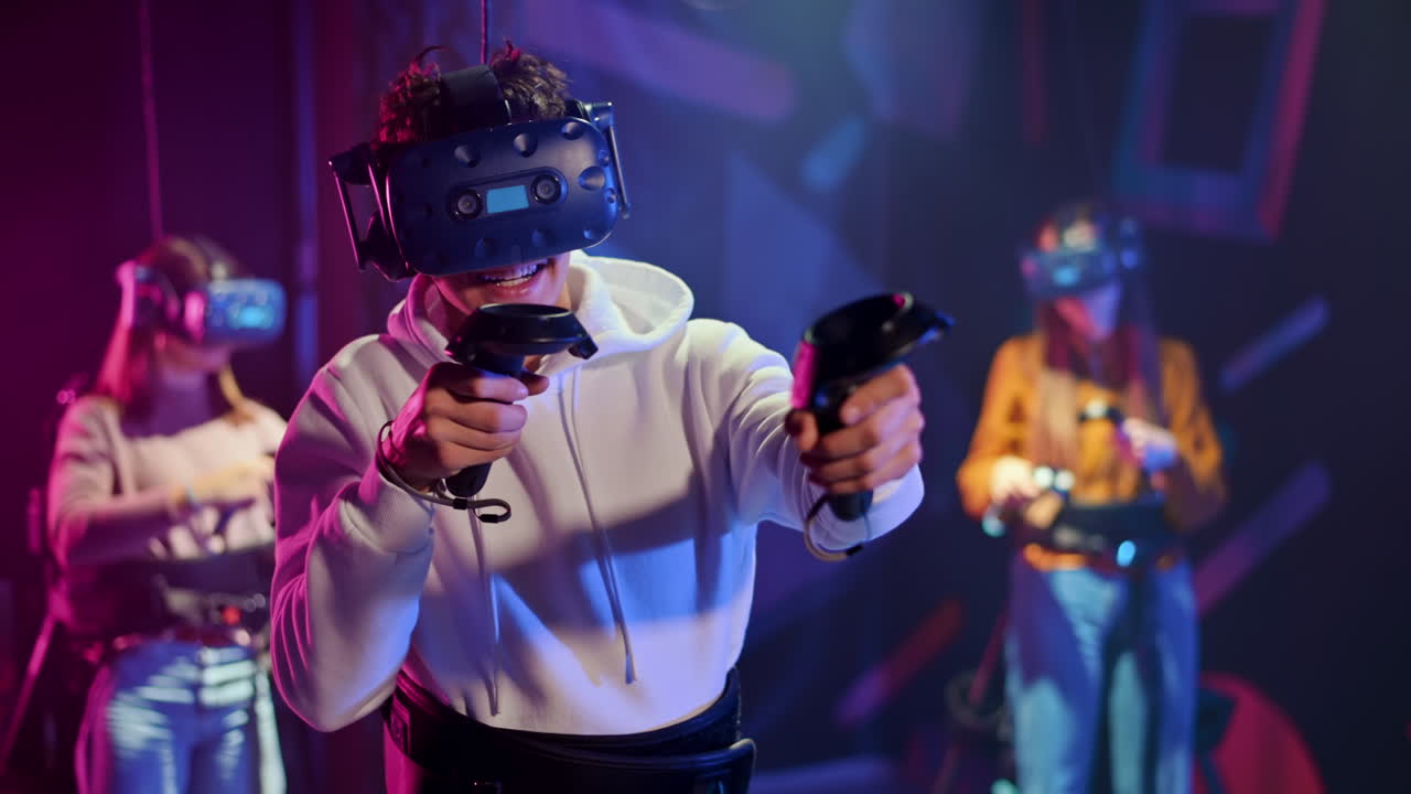 Un bambino felice e interessato gioca su un tapis roulant VR con casco, controller e zaino. Altre persone giocano nelle vicinanze