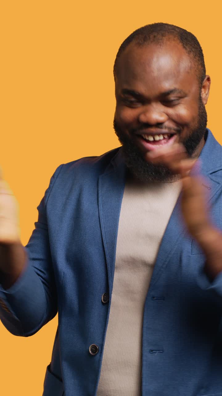 Vertical video Joyful man happily clapping hands, ecstatic, studio background