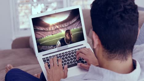 hombre viendo un juego de fútbol en una computadora portátil