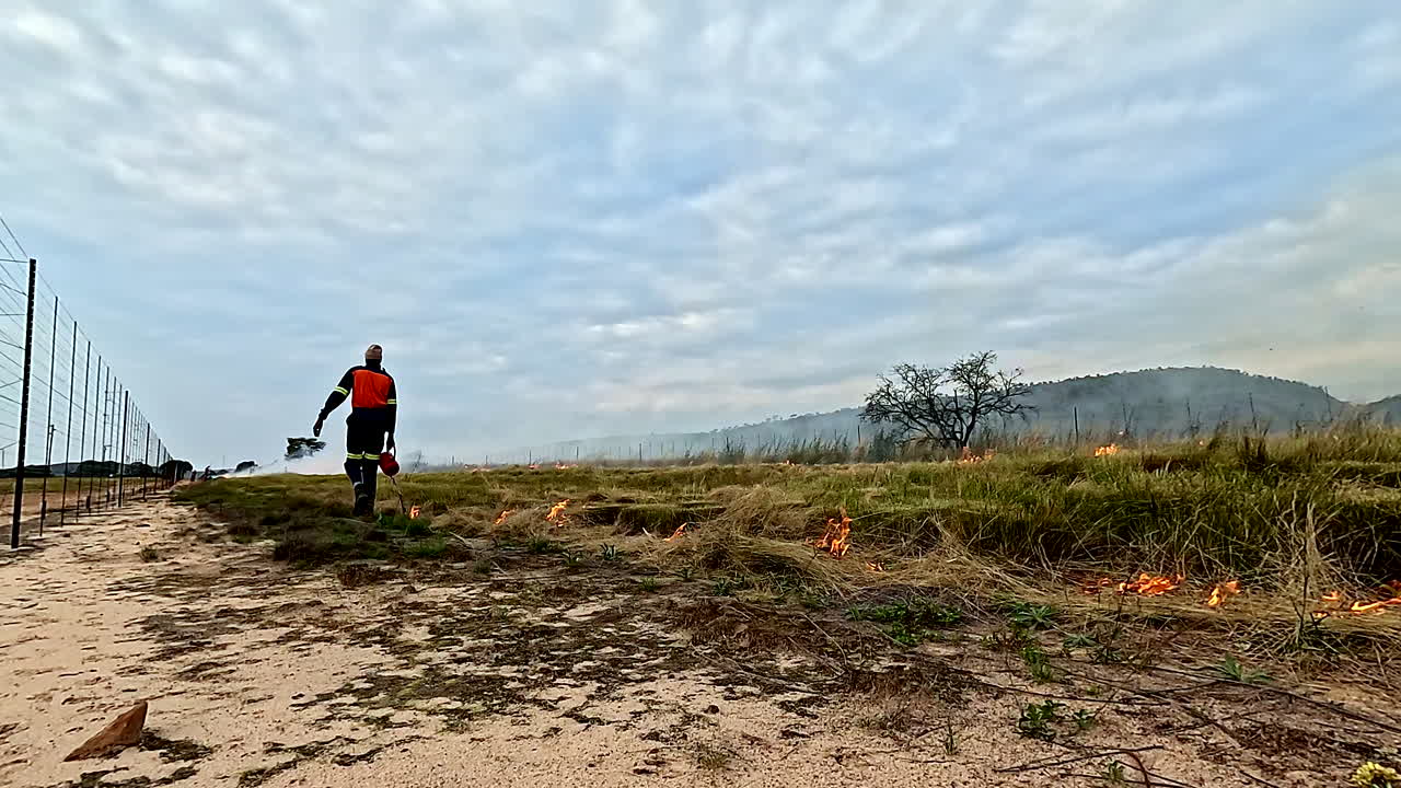 Firefighter manages wildfire along fence line of African wilderness park zone