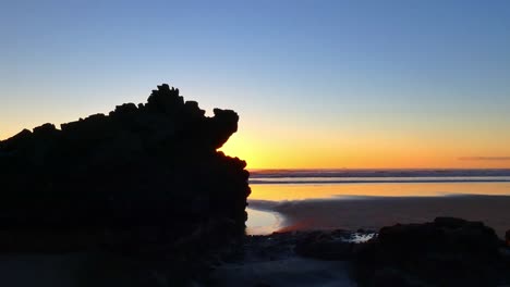 Magnificent-sunrise-creates-'fire-breathing-dragon'---rock-silhouette---Sumner-Beach,-New-Zealand