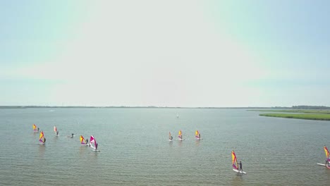 Toma-Aérea-De-Windsurfistas-En-Un-Lago-Tranquilo-Durante-El-Verano