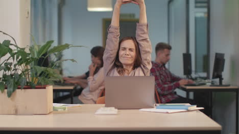 business woman trying to relax at coworking. pretty woman stretching after work.