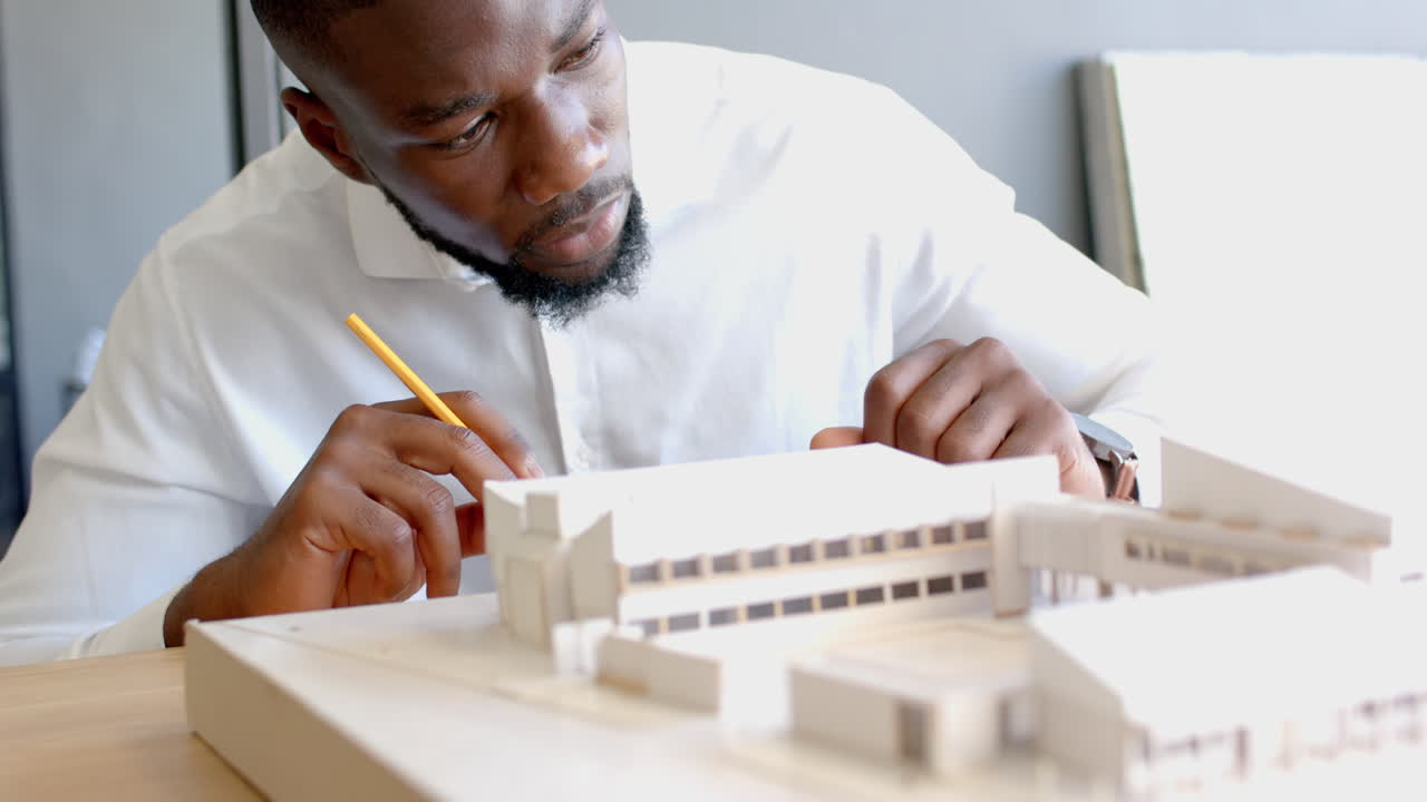 Architect working on building model, carefully measuring and designing structure