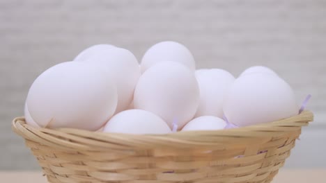 white eggs rotate in basket on light background close up