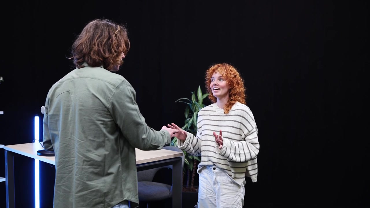Giovane uomo e donna che parlano e si stringono la mano in uno studio