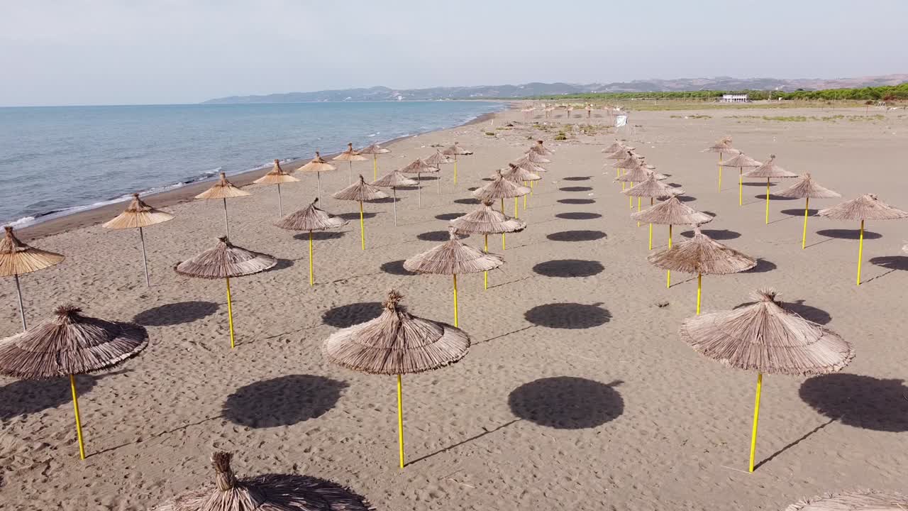 sombrillas en la playa de arena abandonada en albania durante la temporada de verano tardío - vista aérea