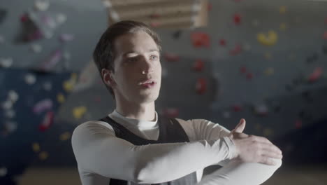 focused young sportsman doing warmup exercises and stretching arm in a bouldering gym