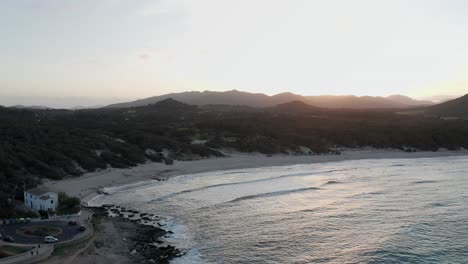 Playa-De-Mallorca-Cala-Aguila-Al-Atardecer-En-Una-Cálida-Tarde-Con-Olas-Rompiendo-En-La-Playa-Y-La-Puesta-De-Sol-Detrás-De-Montañas-Distantes