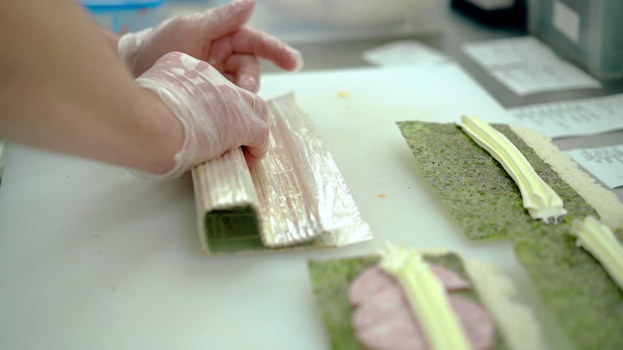 요리사 는 일본식 롤 을 준비 하고, 마트 를 사용 하여 밖 에  ⁇  을 감는다