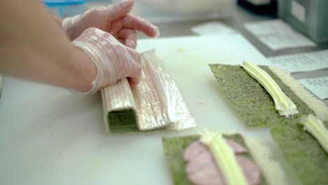 cook prepares a japanese roll wraps rice outside using a mat