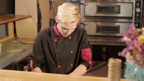 man cooking pizza in the kitchen of restaurant