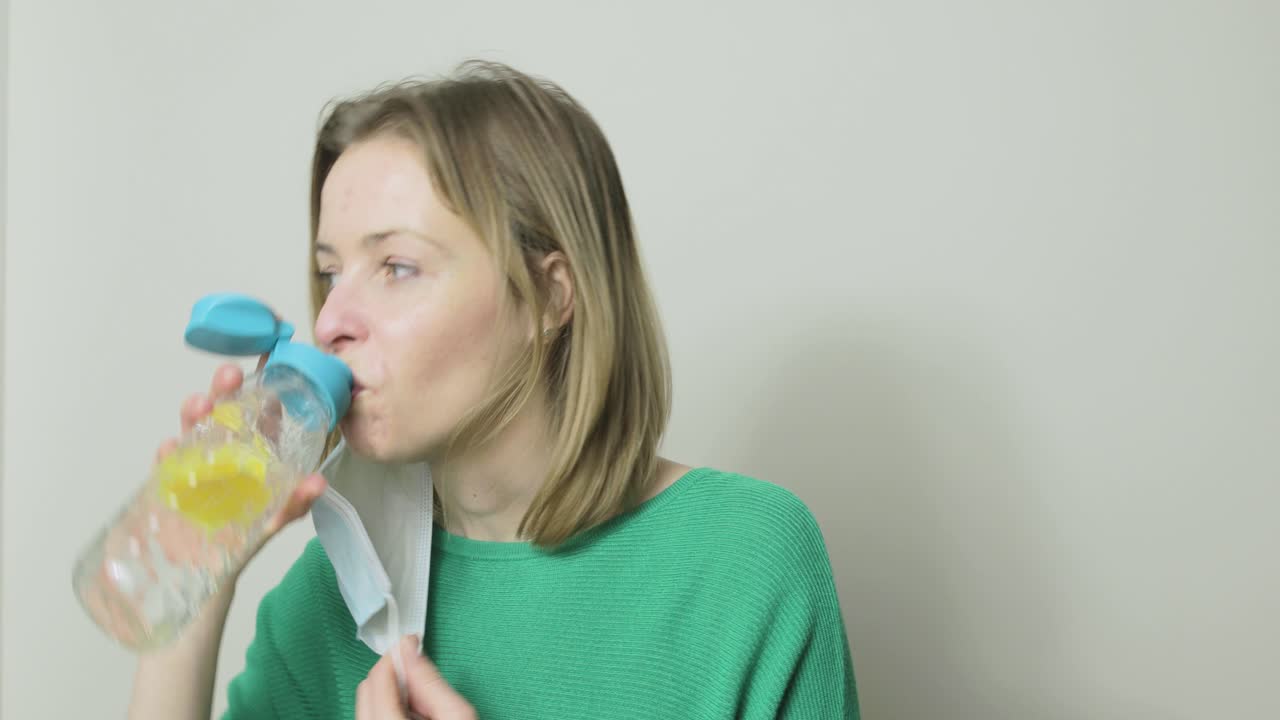 Video divertente di una donna che dimentica di togliersi la mascherina prima di bere, si sorprende e sembra imbarazzata