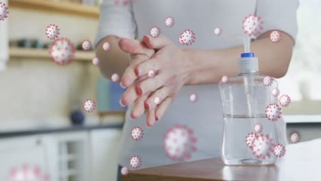 animation of covid 19 virus cells over caucasian woman disinfecting hands