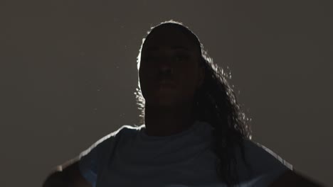 backlit head and shoulders studio portrait shot of young woman dancing in spotlight 3