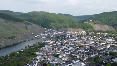 Vuelo-Aéreo-Sobre-La-Pintoresca-Ciudad-De-Bernkastel-Kues,-Río-Mosela-En-Segundo-Plano