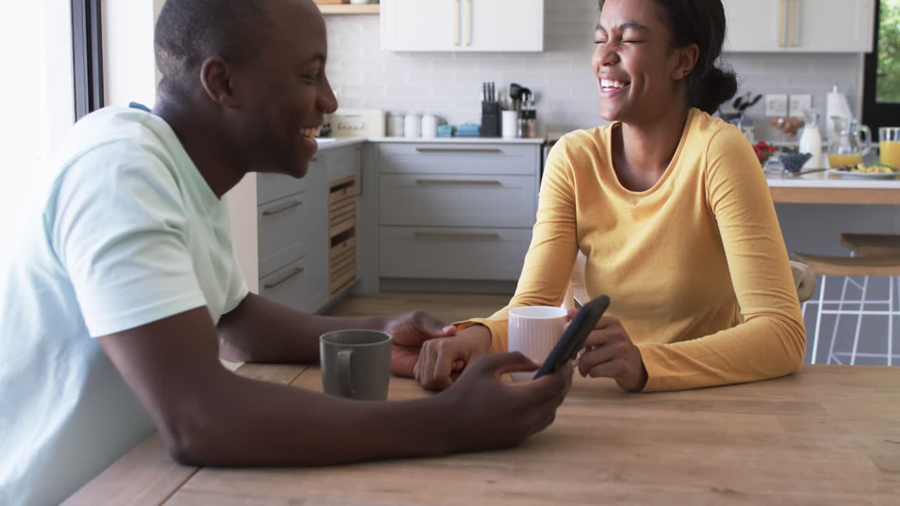 African American couple enjoys a moment in the kitchen, drinking coffee