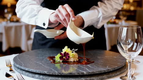 a chef skillfully plates a gourmet dessert with sauce at a fine dining restaurant