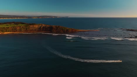 wide aerial pan around jet ski speeding along the ocean around longreef headland, sydney, australia
