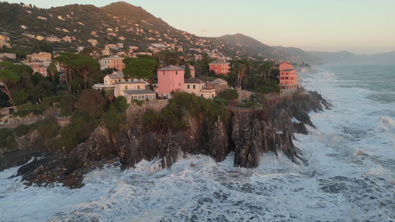 fuertes olas del mar rompiendo en la costa escarpada con casas en la ciudad de génova