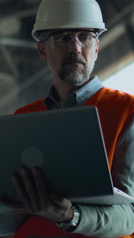 construction worker reviewing laptop in industrial setting