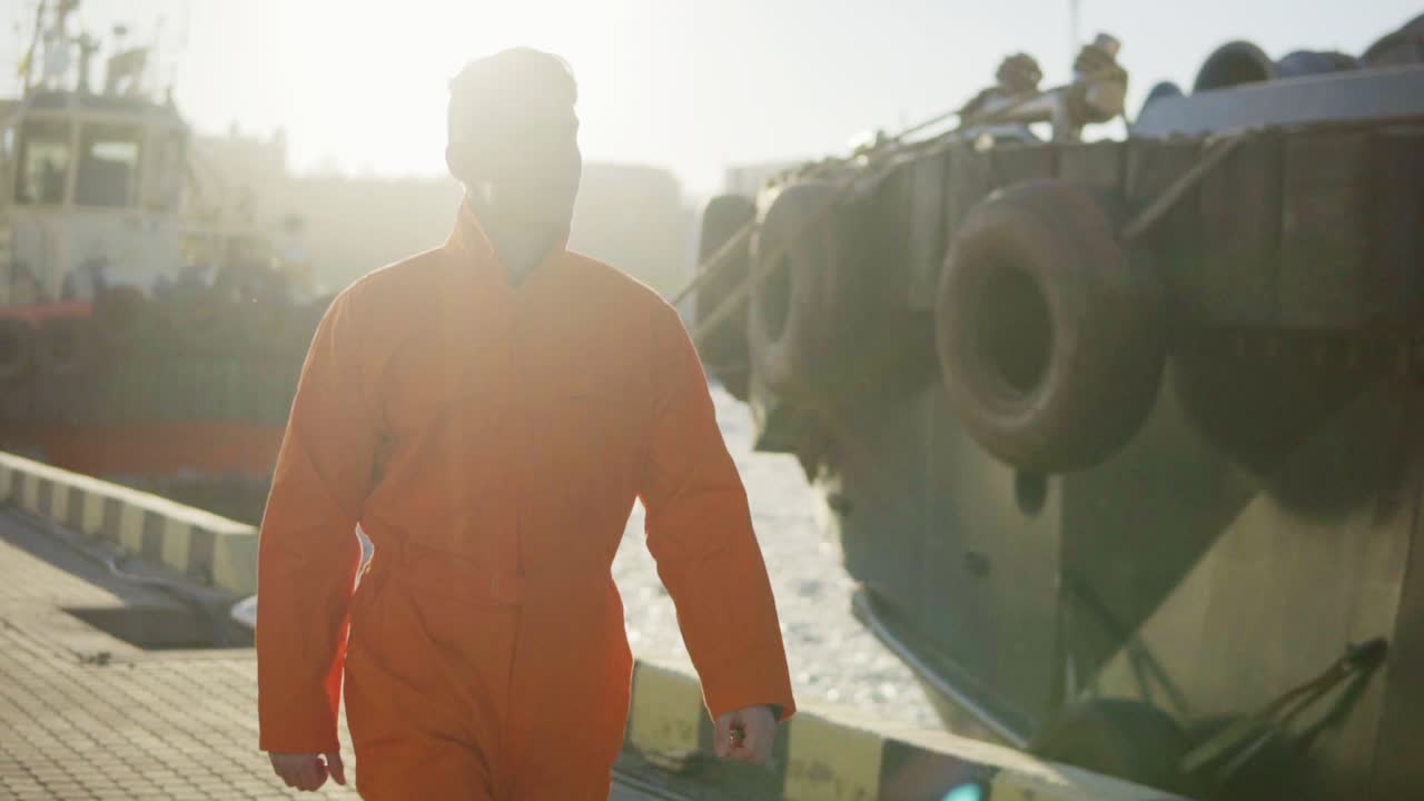 el trabajador del puerto en uniforme naranja está junto al mar.