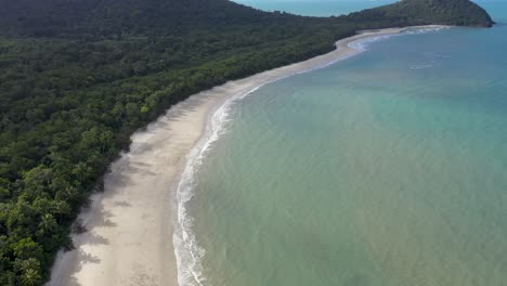 Inclinación-Aérea-Hacia-Atrás-De-La-Tribulación-Del-Cabo-Revelación-De-La-Playa-Soleada-En-La-Selva-Tropical-De-Daintree,-Queensland,-Australia