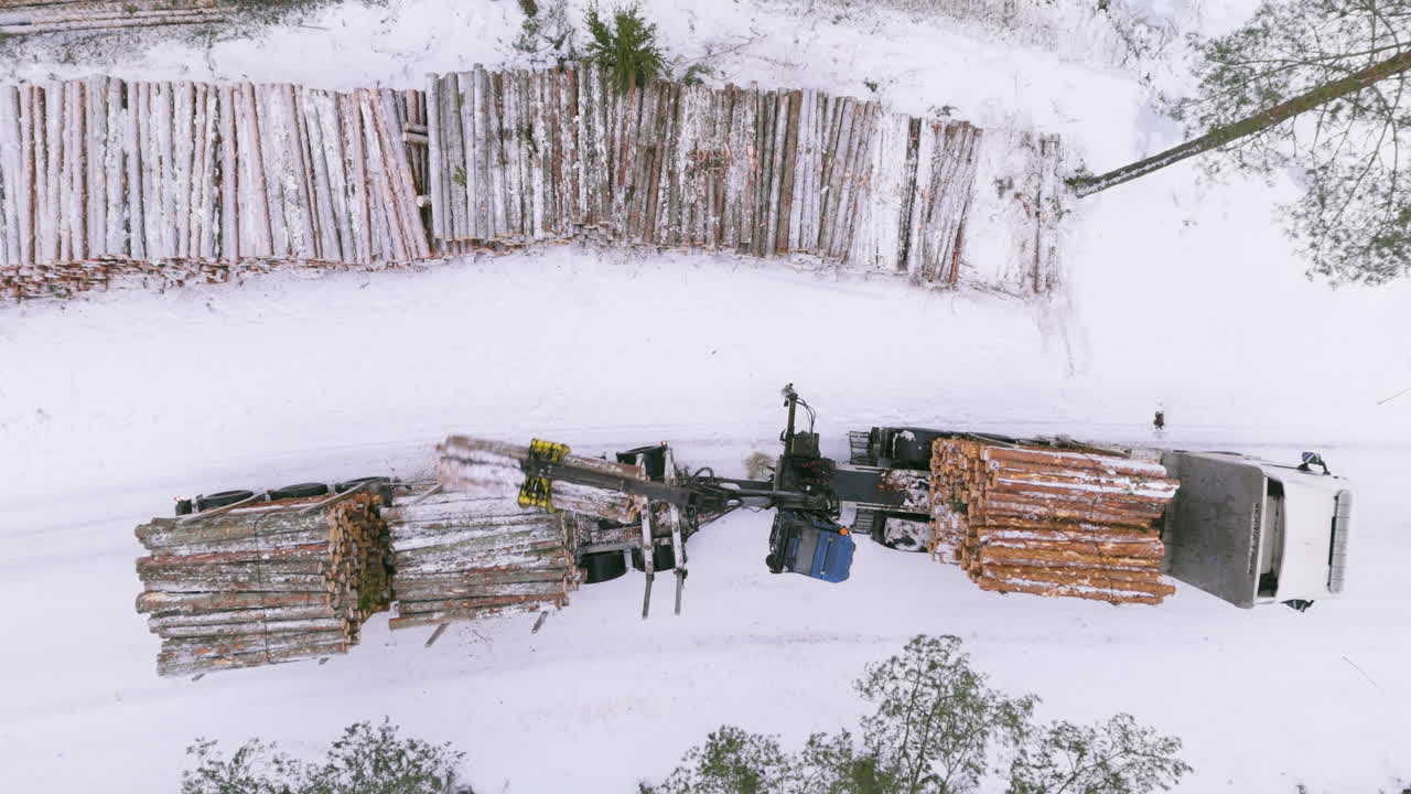 vista de la nieve de invierno del drone riser del cargador de troncos montado en la parte trasera cargando troncos en el camión