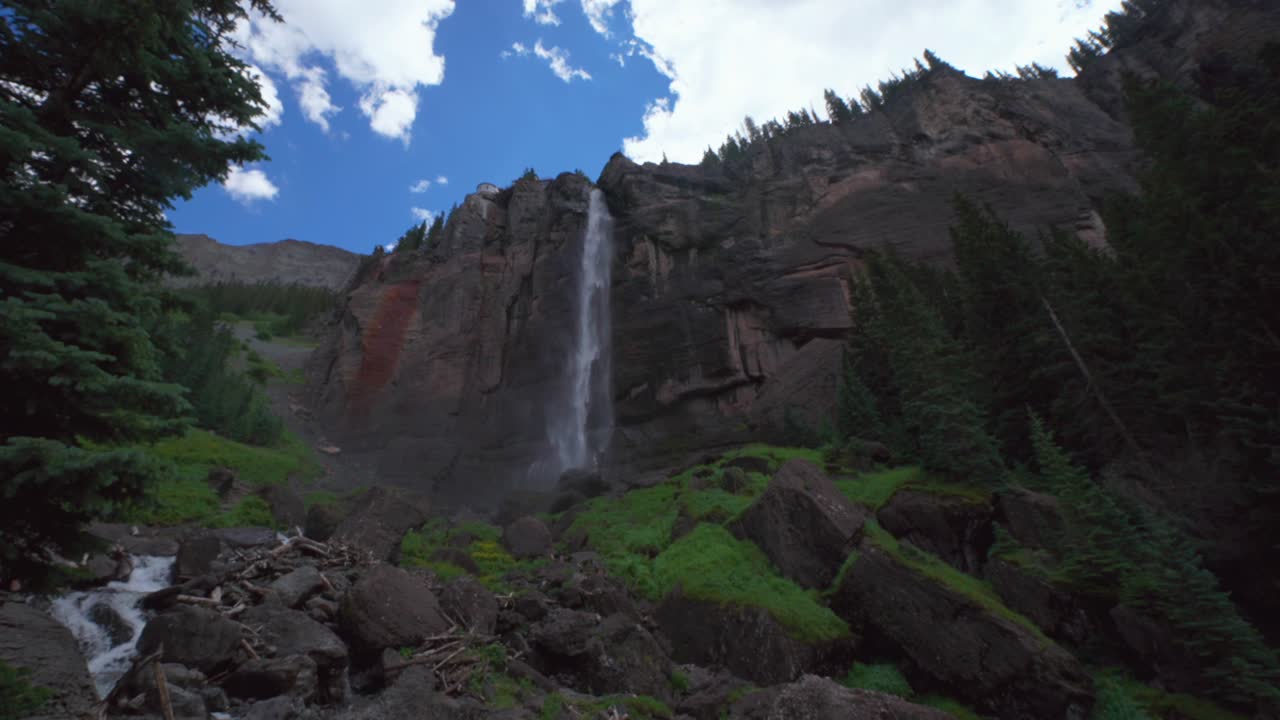 Cloudy shaded Telluride Bridal Veil Falls Waterfall Black Bear Pass Road Colorado landscape pan down mist spray Ouray Ridgway Box Canyon cliffside hydro power house 4wd hiking blue sky boulders creek