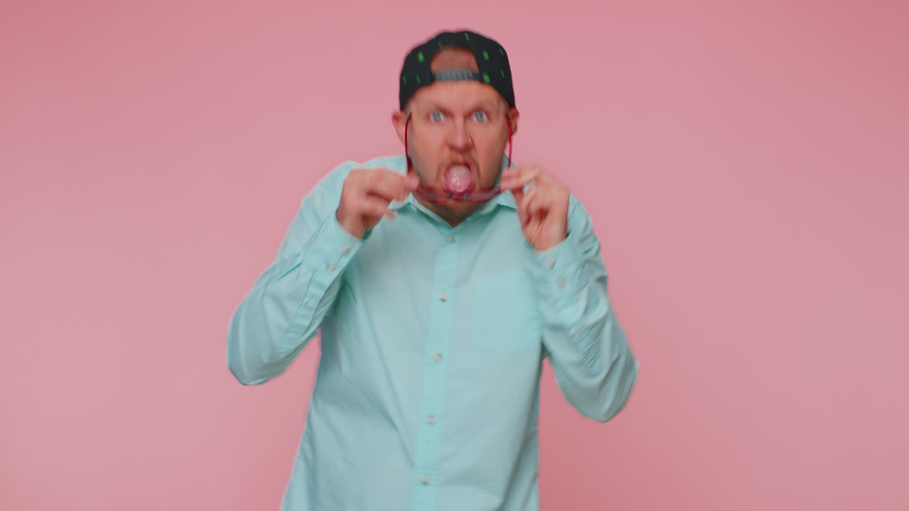 Funny joyful man making playful silly facial expressions grimacing fooling around showing tongue