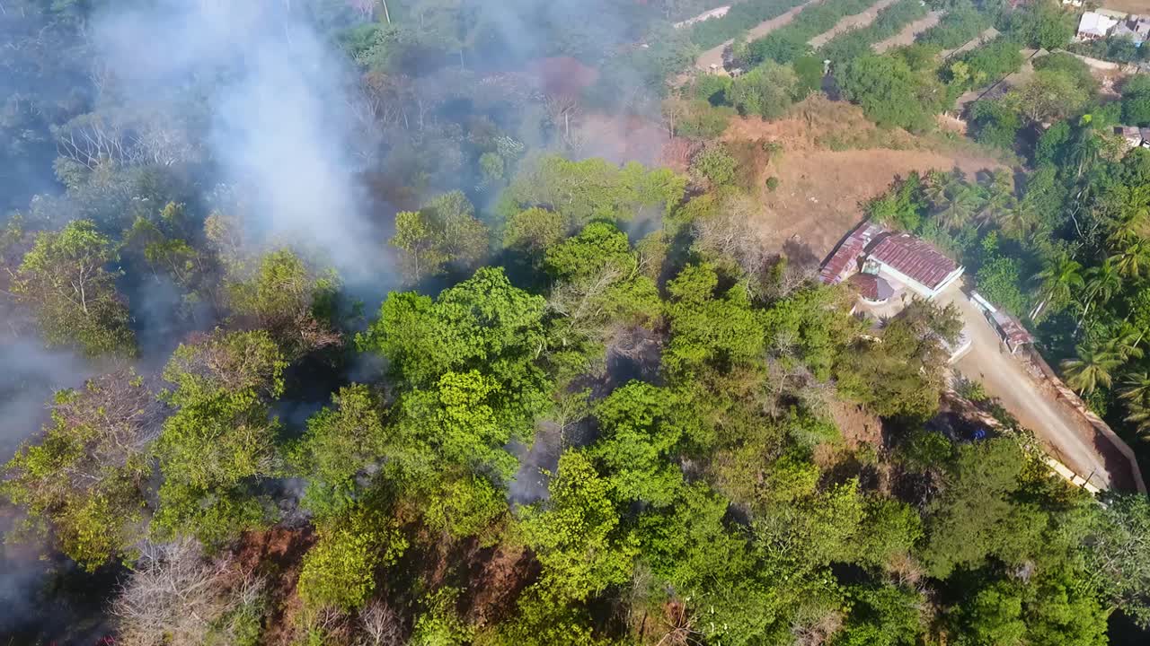 vista aérea de un incendio forestal tropical cerca de una granja, día soleado, en américa del sur - seguimiento, disparo de drones