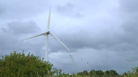 Wind-turbine-against-stormy-sky-with-rise-up-from-grass-level-on-windy-day