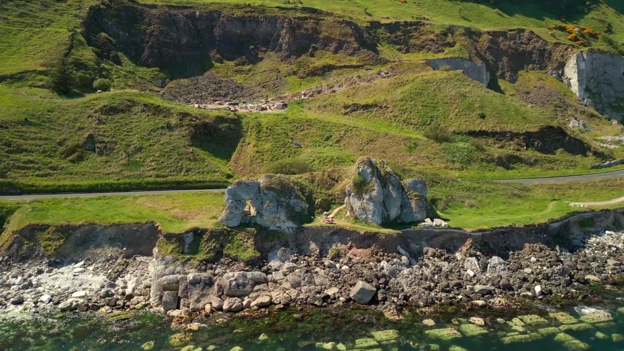 Descending aerial video of Madman's Window on the Causeway Coastal Route in County Antrim, Northern Ireland, UK, on a bright and sunny day. Filmed in 4K, 60FPS and with Rec709 color.
