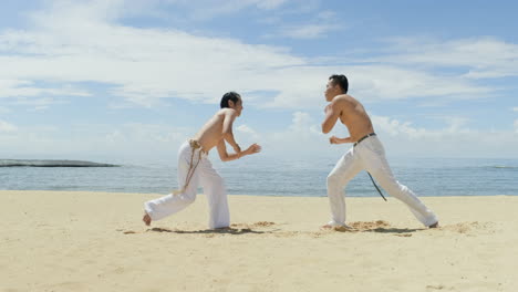 dos hombres bailando capoeira en la playa