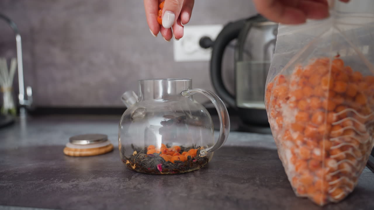 Berry Tea Preparation, Preparing Herbal Tea With Dried Goji Berries On Kitchen Counter, An Intimate Home Process Involving Scattering Dried Goji Berries Into Glass Teapot Surrounded By Warm Tones