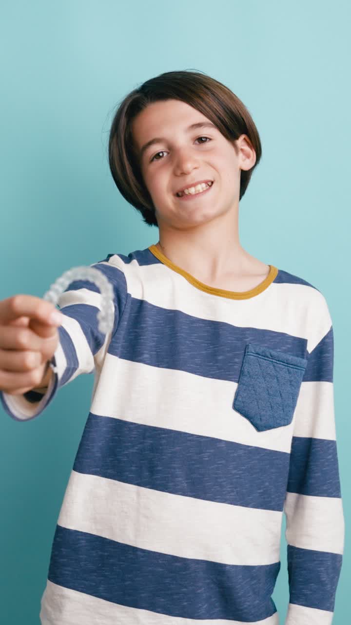 Ragazzo felice che sorride e mostra un allineatore dentale trasparente