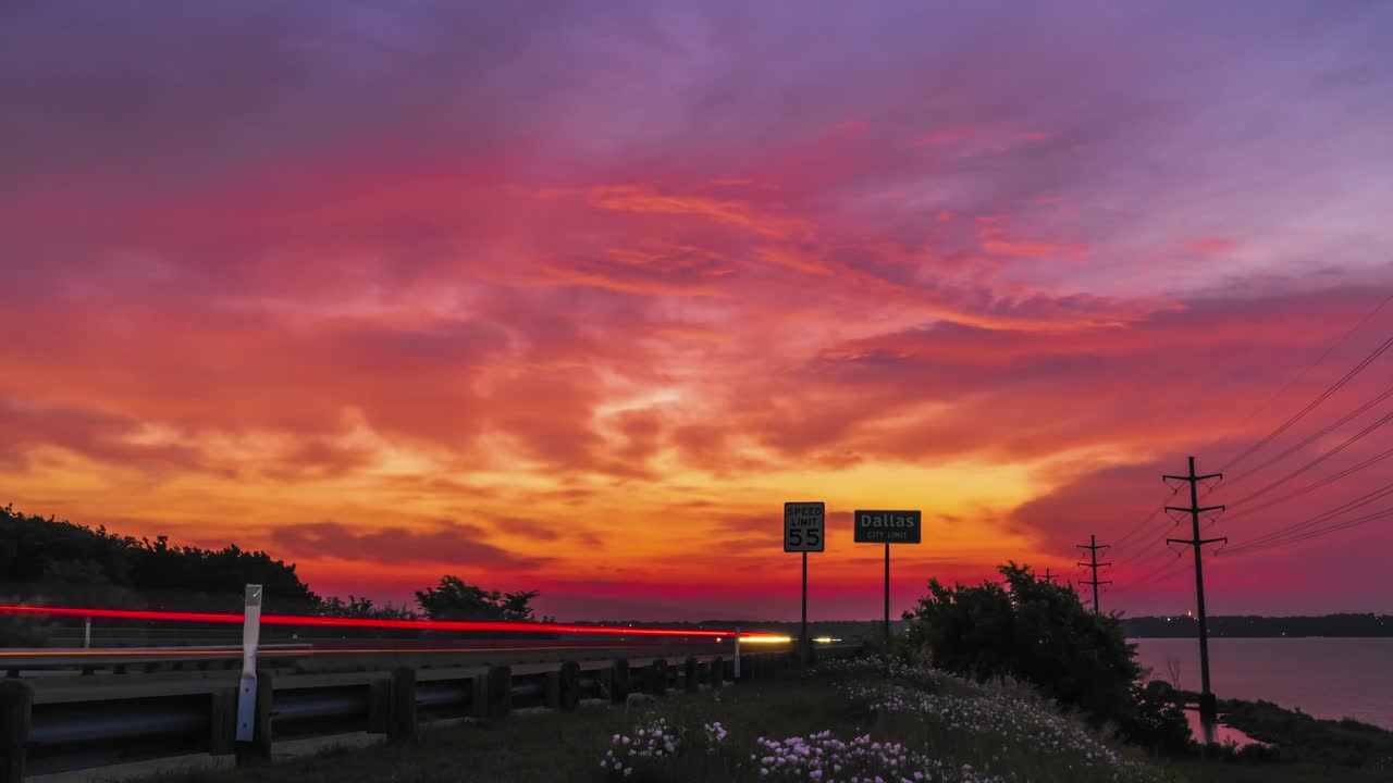 los coches se acercan a lo largo de la autopista en el rastro de luz borroso delante de la épica puesta de sol cielo en el camino a dallas