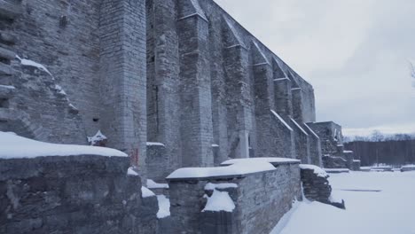 stone wall in ancient covent ruins covered in snow during overcast day, tracking right shot