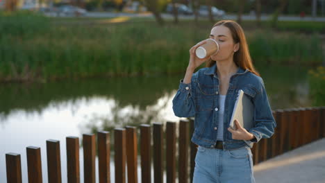 woman enjoying coffee break in the park with a laptop