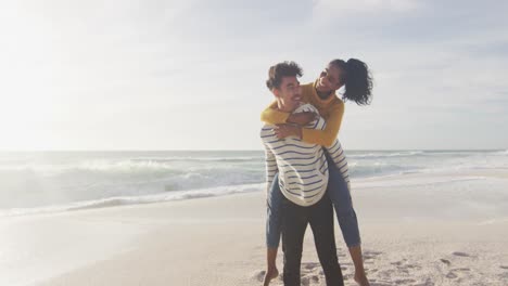 Un-Hombre-Hispano-Feliz-Llevando-A-Una-Mujer-A-Cuestas-Y-Divirtiéndose-En-La-Playa