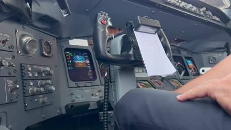 closeup left side view of the hand of a white pilot using the hand microphone to address the passengers during a real flight. modern jet cockpit. 4k