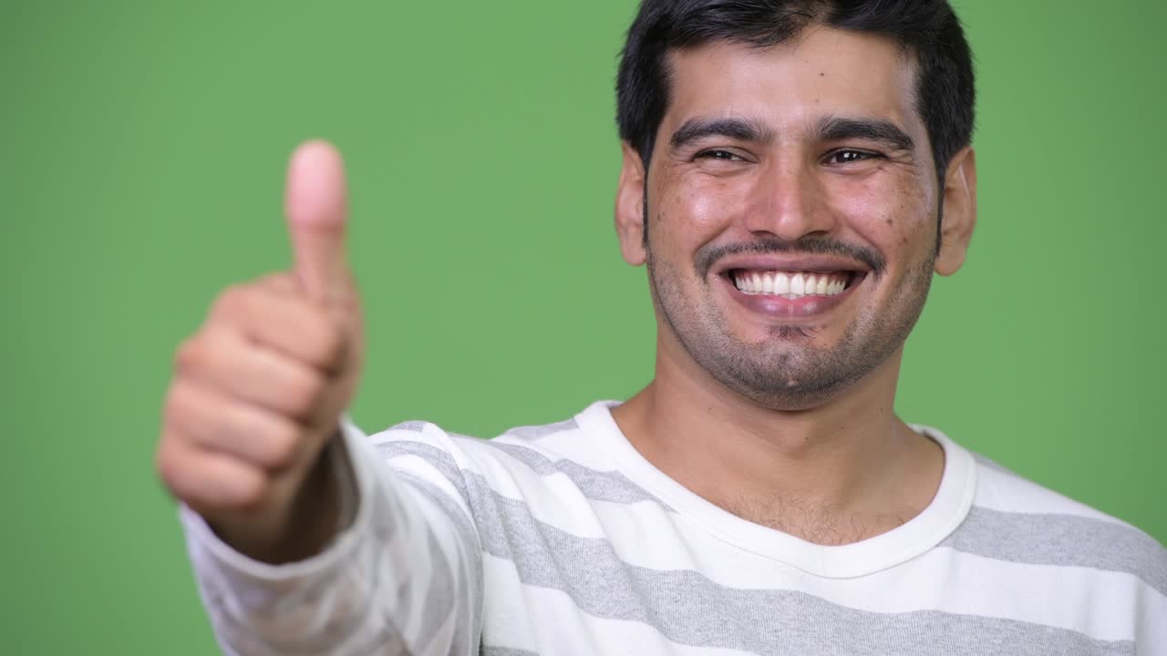 Young handsome Persian man giving thumbs up