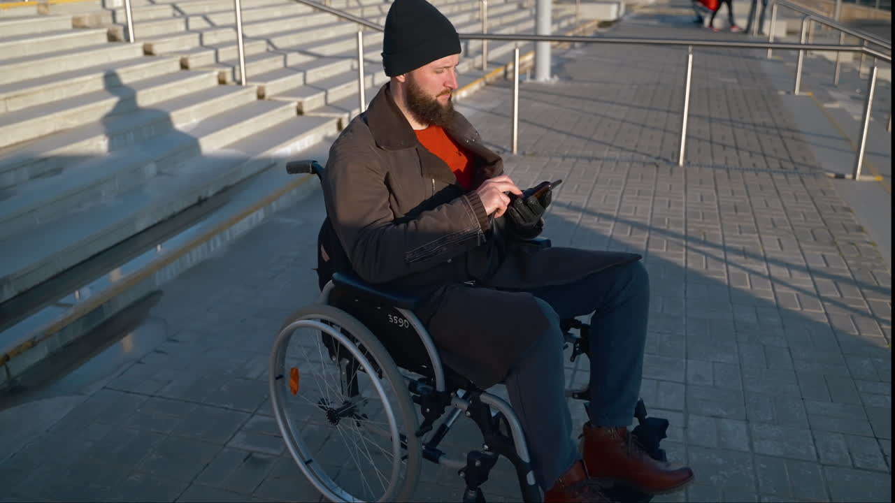 hombre en silla de ruedas usando un teléfono inteligente en un estadio