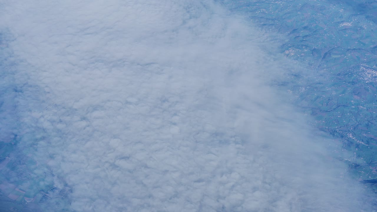 Europe’s textured landscape contrasts soft clouds during high altitude flight