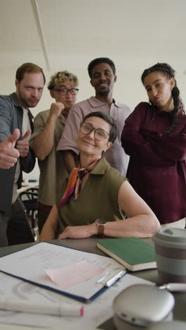 a diverse group of cheerful professionals posing with positive gestures in an office setting