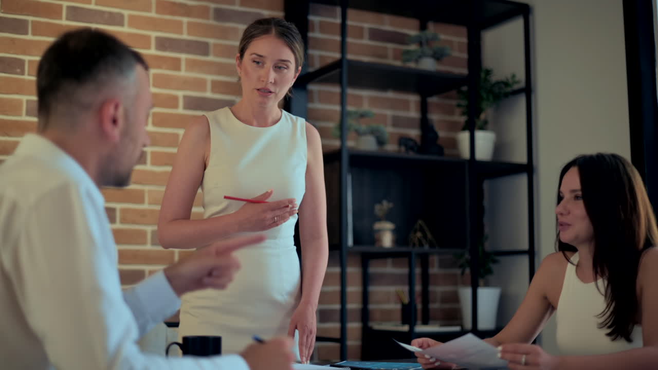Mulher de pé conversando com os colegas de trabalho em uma mesa em um escritório
