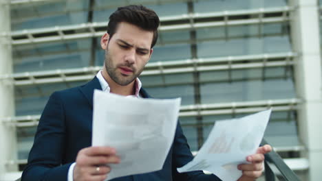 serious businessman reading documents on the street